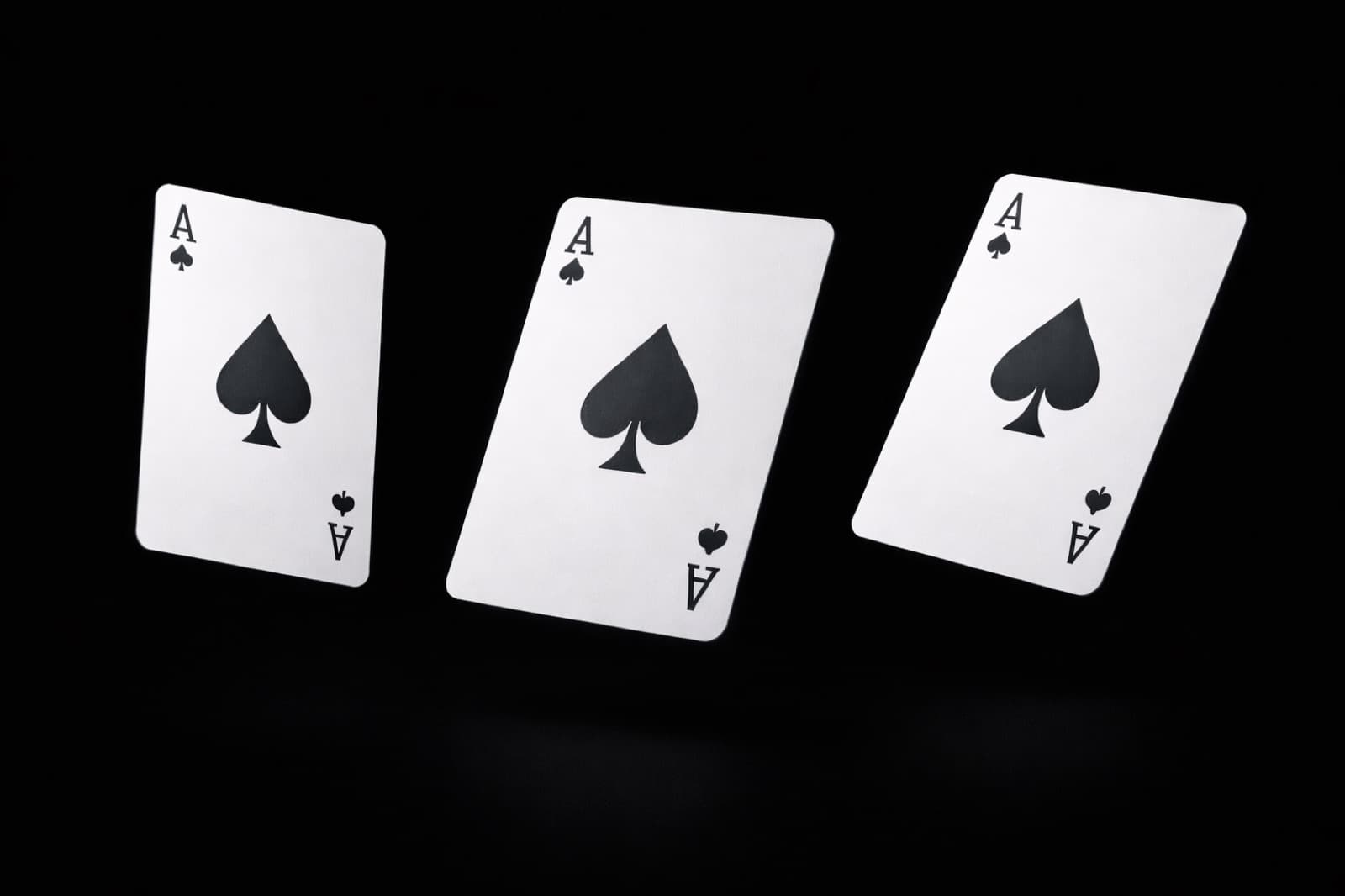 Three ace of spades cards suspended mid-air against black